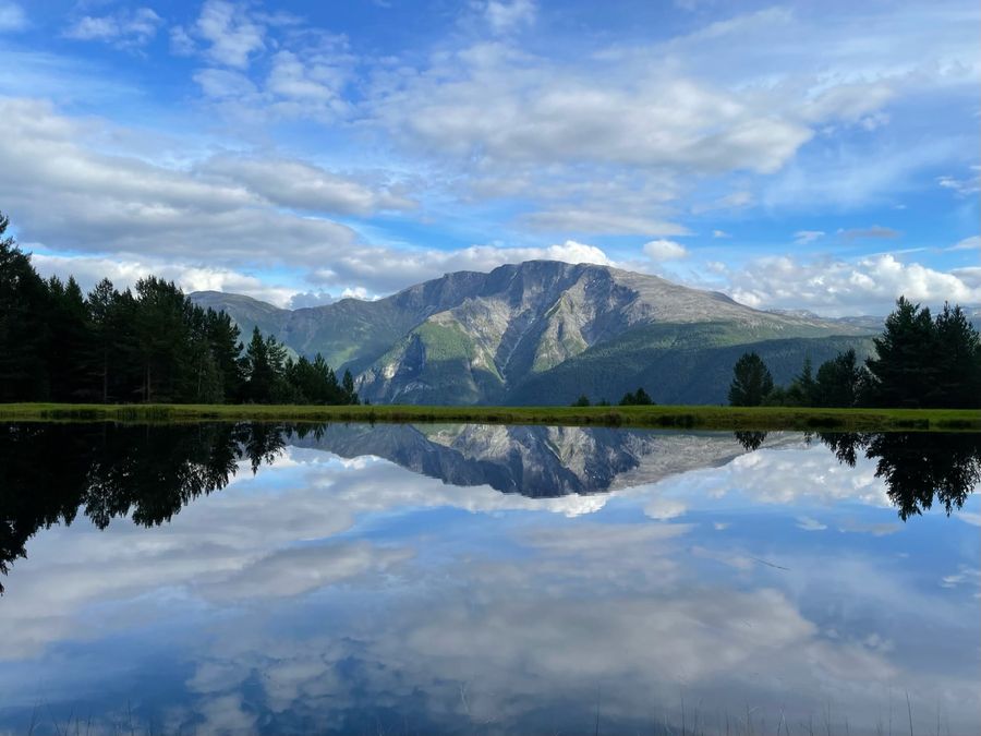 Mountain and clouds mirrored in a still pond in Sogndal, Norway